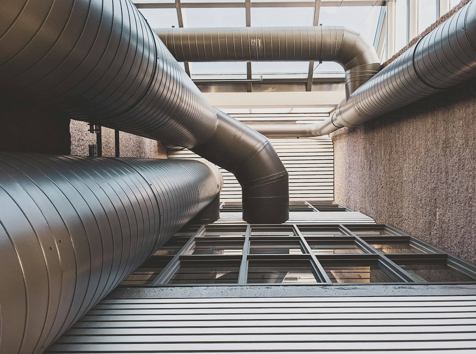 Polished spiral sheet-metal ductwork running through a commercial atrium