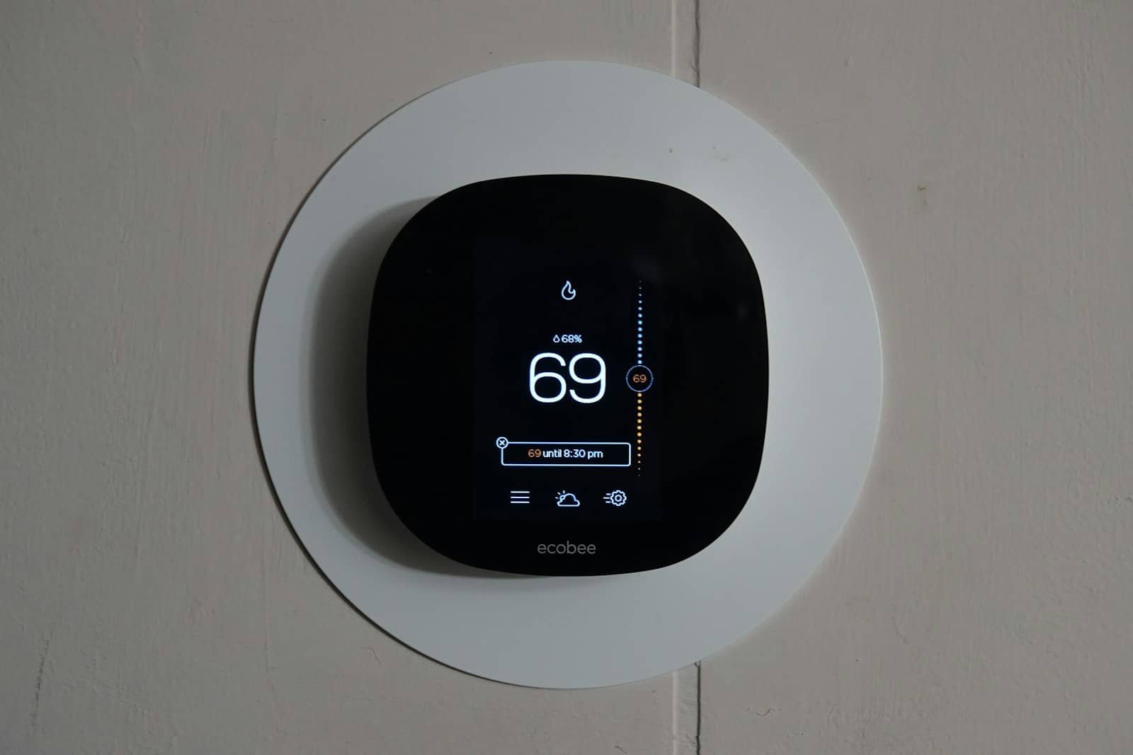 ecobee smart thermostat on a wall, cool blue display reading 69 degrees