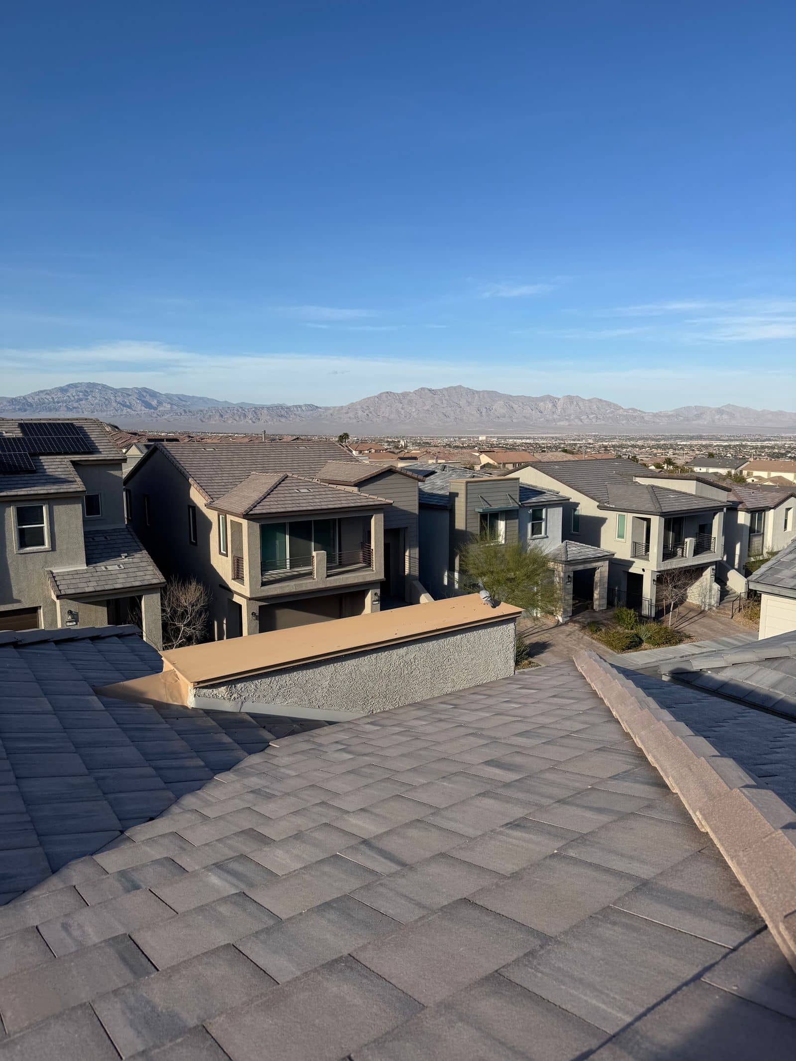 Tile rooftops of two-story stucco homes in the Las Vegas valley with desert mountains on the horizon