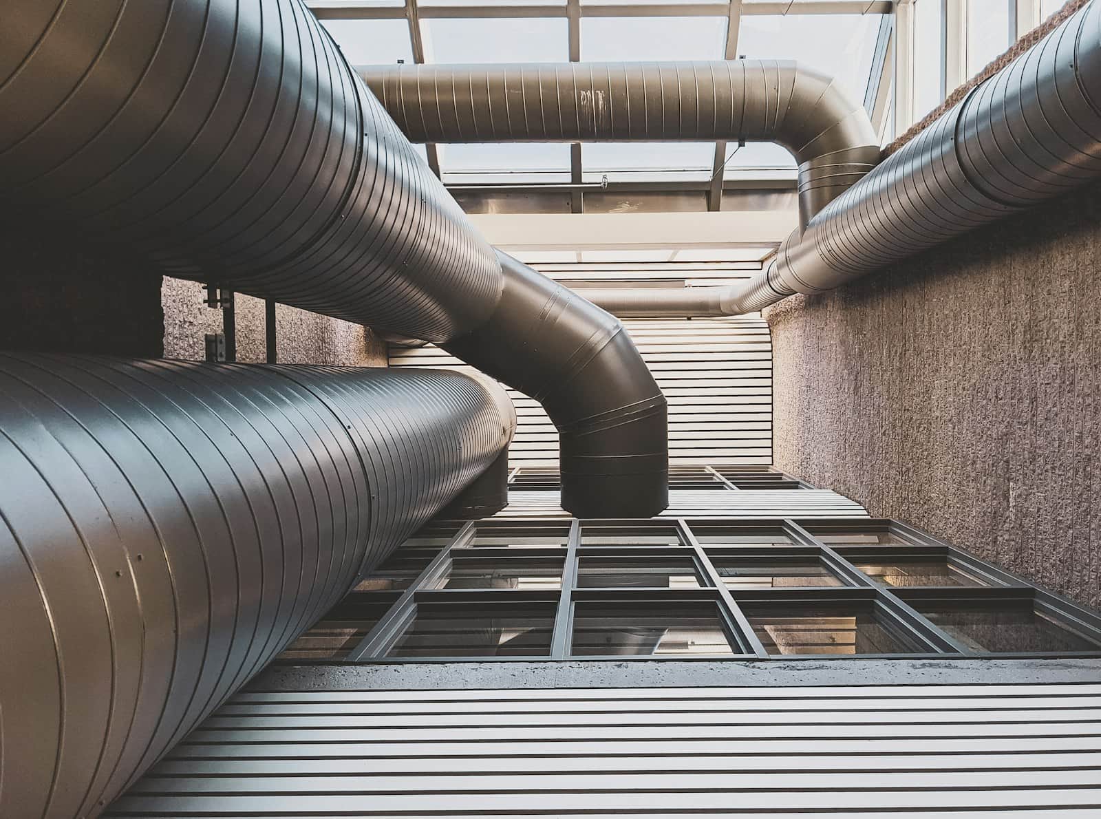 Polished spiral sheet-metal ductwork running through a commercial atrium